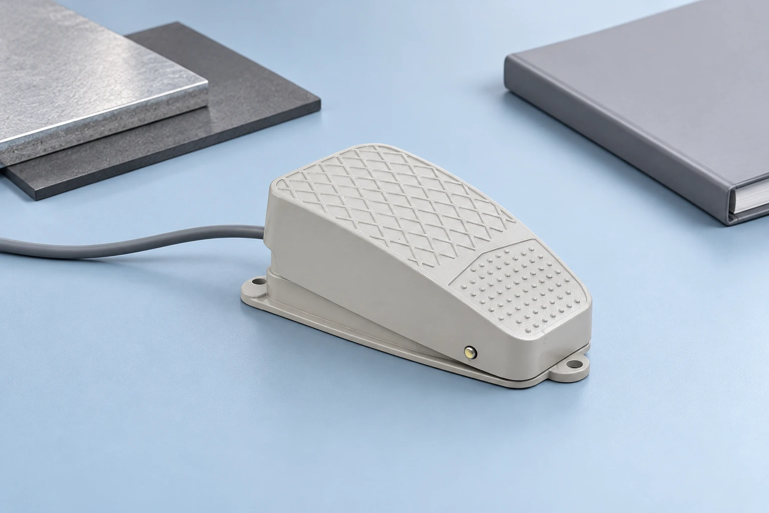 Grey LF reference foot pedal beside separate grey material coupons on pale blue desk